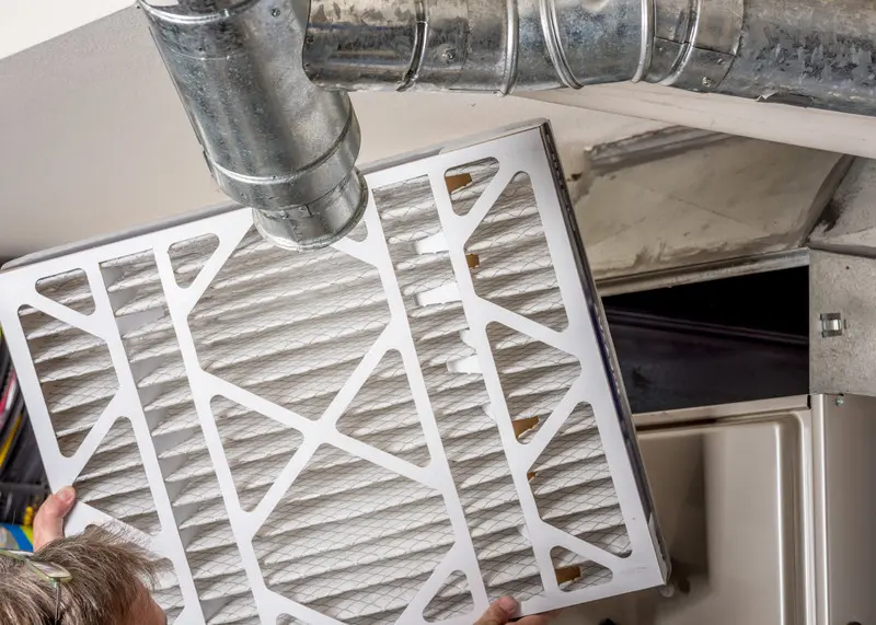 Person replacing the air filter in a whole home air purifier HVAC system.